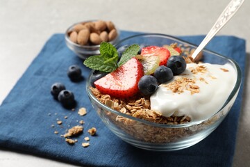 Tasty granola with berries, yogurt and mint on grey table
