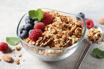Tasty granola with berries, nuts and mint on grey table