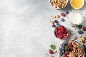 Tasty granola with berries, nuts and mint on grey table, flat lay. Space for text