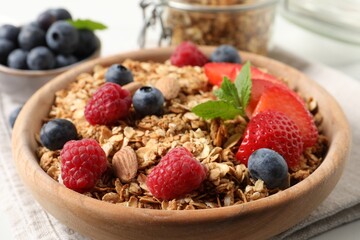 Tasty granola with berries, nuts and mint on white table, closeup