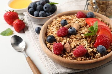 Tasty granola with berries, nuts and mint on white table