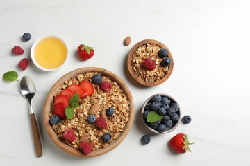 Tasty granola with berries, nuts and mint on white table, flat lay