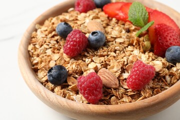 Tasty granola with berries, nuts and mint on white table, closeup