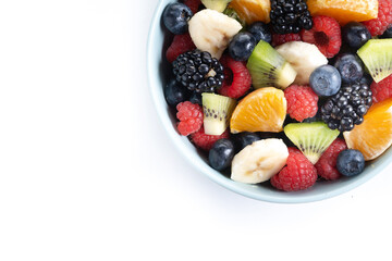 Fruit salad in a blue bowl isolated on white background. Top view. Copy space