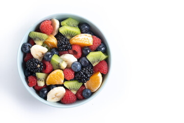 Fruit salad in a blue bowl isolated on white background. Top view. Copy space