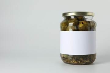 Pickled cucumbers in jar on light background. Space for text