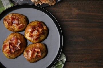 Delicious baked potatoes with bacon on wooden table, top view. Space for text