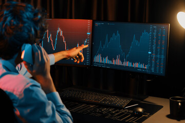 Young investor stock trader calling with broker to invest earning highest profit on current market graph online in real time at neon light modern office, monitor showing investment exchange. Gusher.