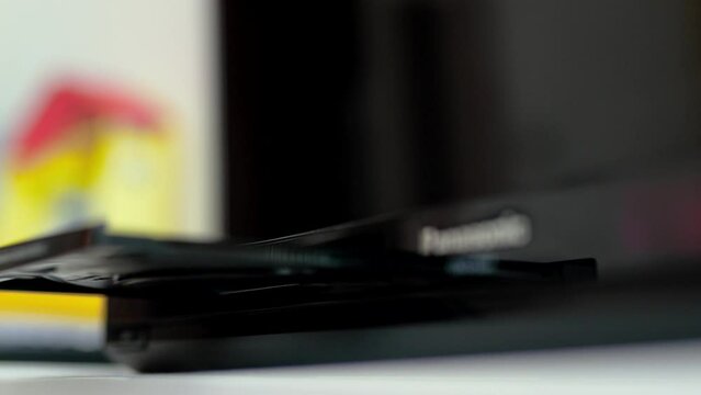 Man puts cd disc  to a video player tray. Physical media concept.