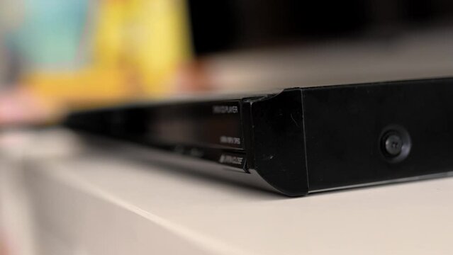 Man puts cd disc  to a video player tray. Physical media concept.