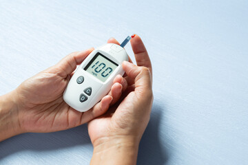 A woman draws blood on his finger and tests it for diabetes. Check high blood sugar levels with a digital blood sugar tester. Health care and medical concept