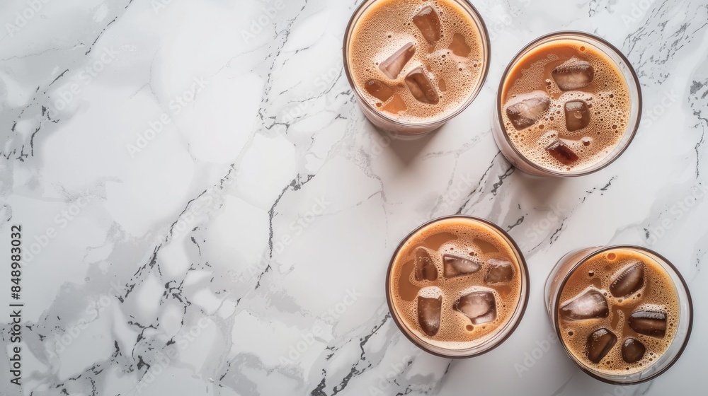 Wall mural cold brew coffee and milk with ice cocoa in three glasses on marble surface top view with empty spac