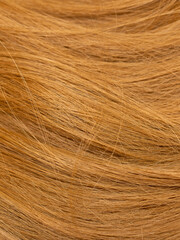 Red hair close-up as a background. Women's long orange hair. Beautifully styled wavy shiny curls....