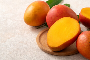 Fresh slice cut juicy mango on gray table background with leaf.