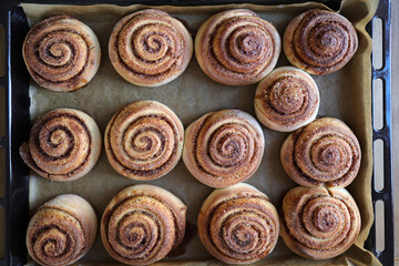 preparing homemade round cinnamon scrolls in a rectangular black baking pan, top veiw