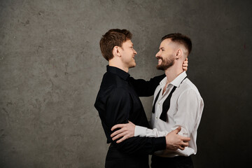 Two men in suits, embracing, against a concrete backdrop.