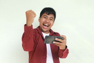 Smile and happy face of Young Asian man when playing game at phone in hand.