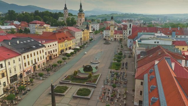 Flying over Banska Bystrica old town - slovak national uprising square, colorful old houses and Church of the Assumption. Aerial drone shot of Banska Bystrica city center, Slovakia