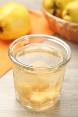 Delicious quince drink in glass and fresh fruits on wooden table, closeup