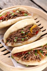 Delicious gua bao in bamboo steamer on wooden table