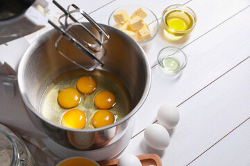 Making dough. Raw eggs in bowl of stand mixer and ingredients on white wooden table, space for text