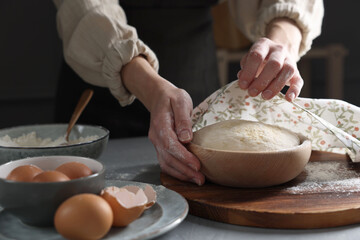 Fototapeta premium Woman covering dough with napkin at grey table, closeup
