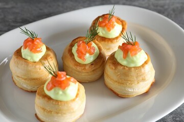Delicious puff pastry with avocado cream, salmon and dill on grey table