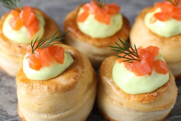 Delicious puff pastry with avocado cream, salmon and dill on table, closeup