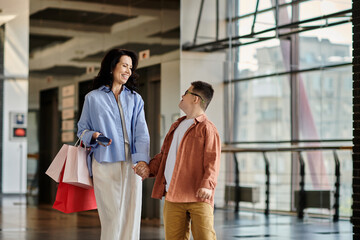 Fototapeta premium A mother and her son with Down syndrome share a happy moment while walking through a shopping mall, holding hands.