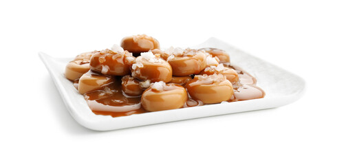 Plate with tasty candies, caramel sauce and salt isolated on white