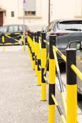 Urban metal fencing in black and yellow. It separates the pedestrian area from the roadway and cars. City fence.