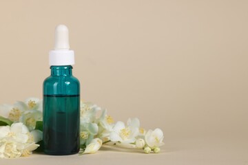 Essential oil in bottle and beautiful jasmine flowers on beige background, space for text