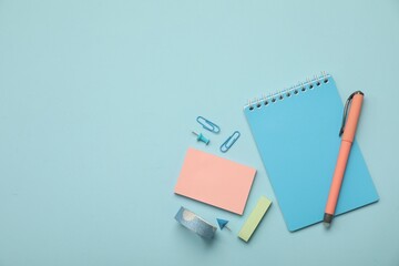 Flat lay composition with notebook and different stationery on light blue background, space for text