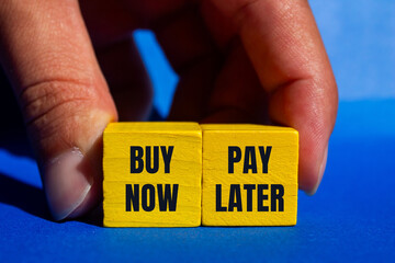 Buy now pay later message written on yellow wooden cubes with blue background. Conceptual buy now...