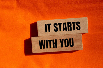 It starts with you message written on wooden blocks with orange background. Conceptual it starts with you symbol.