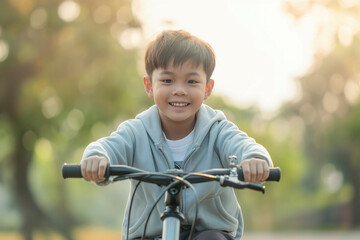 Obraz premium A young boy riding a bicycle in a park, smiling and enjoying the ride on a sunny day.