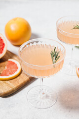 Refreshing grapefruit rosemary lemonade, served in crystal glasses on white table background....