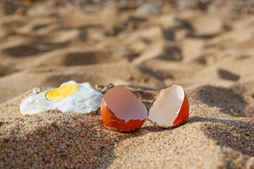 A chicken egg was fried in the sand. Hot weather on the beach.