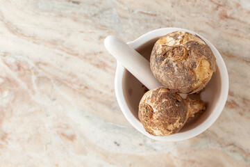 Top-view of Dry Organic Wild onion or Indian squill (Drimia indica), in white ceramic mortar and pestle, on a marble background.