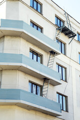 A rooftop access ladder ascends between building balconies, merging architecture with function