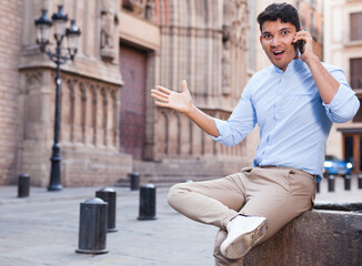 Modern guy walks in city and communicates on smartphone