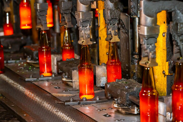 Glass factory, production of glass containers. Molten glass is blown into molds. Robotics in industry. Modern technologies, robotic machines produce products. Technological work at the plant.