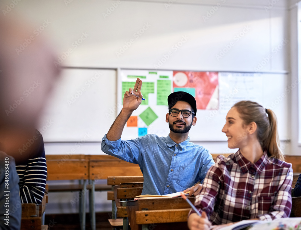 Wall mural Male person, hand raised and education at university, college or school in classroom for question. Student, group and confident with textbook on desk for exam, project or tutorial in learning english