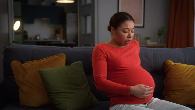 African American woman female pregnant girl at home pregnancy lady future mother unhappy feeling bad belly ache pain painful cramps start of contractions medicine problem childbirth health trouble