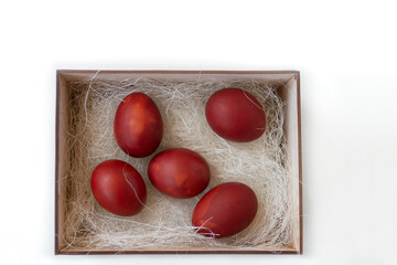 Fresh red eggs and some straw in a wooden crate on a white background. Chicken eggs. Easter concept .Top view