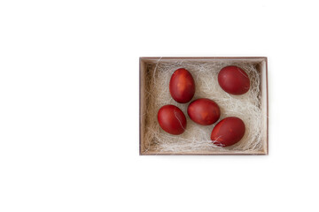 Fresh red eggs and some straw in a wooden crate on a white background. Chicken eggs. Easter concept .Top view