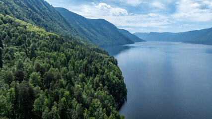 summer panoramic landscape of mountains and forest and waterfall against the sky in the area of ​​Lake Teletskoye in Altai