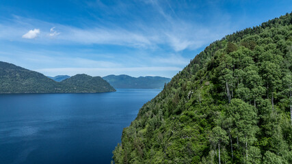 summer panoramic landscape of mountains and forest and waterfall against the sky in the area of ​​Lake Teletskoye in Altai