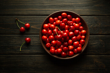 Fresh ripe sweet cherries in a bowl on a black table. Healthy food or dessert concept
