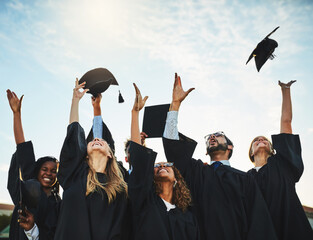 Students, graduation and caps in sky for celebration, university achievement or ceremony with happy...
